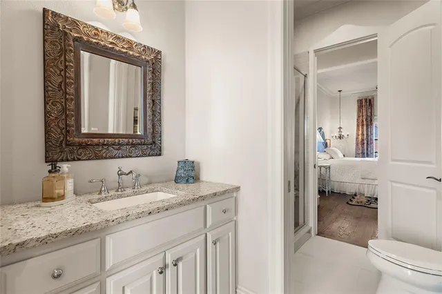 a en suite bathroom with a granite countertop sink and a mirror