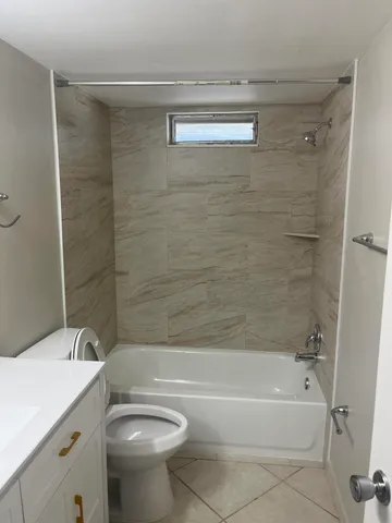 a bathroom with a granite countertop bathtub shower sink vanity and toilet