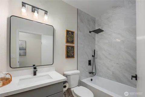 a bathroom with a granite countertop sink toilet a mirror and shower