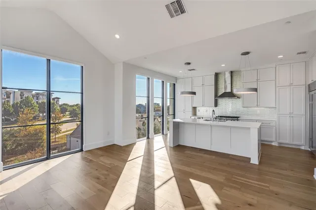 a large kitchen with stainless steel appliances kitchen island granite countertop a refrigerator and cabinets
