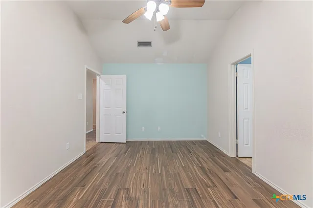 a view of a room with wooden floor a chandelier fan and a window