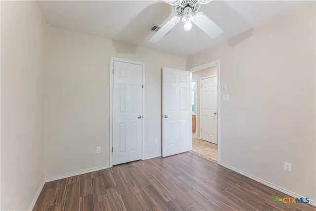 an empty room with wooden floor and fan