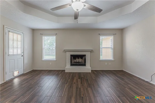 an empty room with wooden floor fireplace and windows