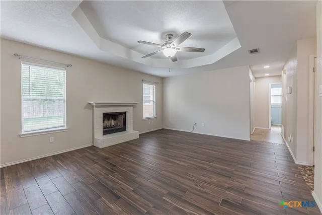 a view of an empty room with wooden floor fireplace and a window
