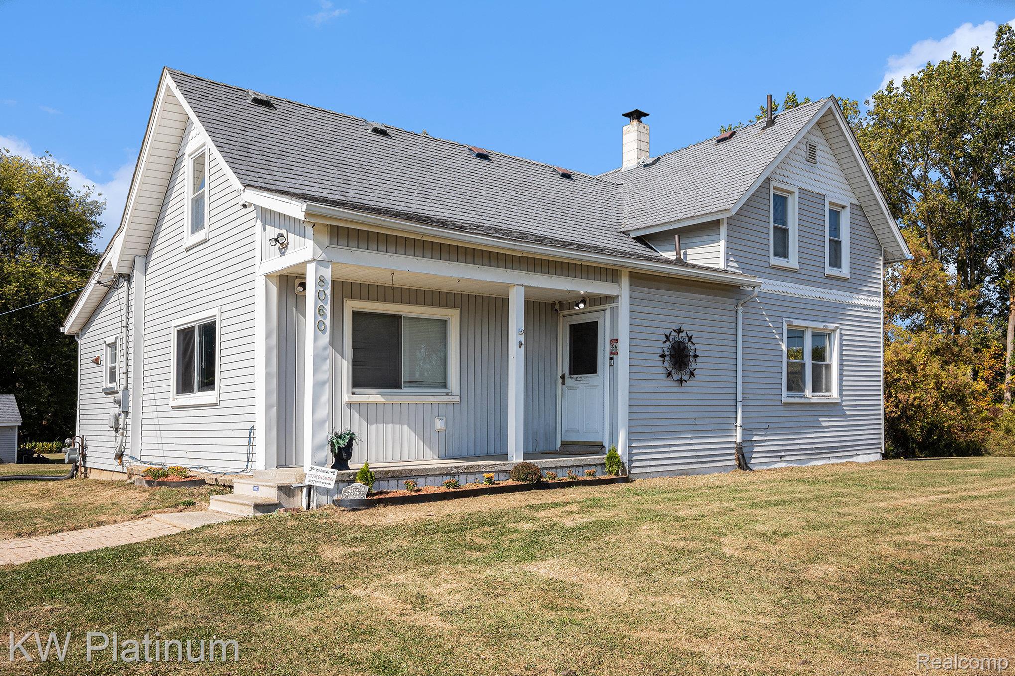 8060 Brockway Road Melvin, MI 48454 - Photo 2 of 39 View of front of house featuring a front yard, a shingled roof, a porch, and a chimney