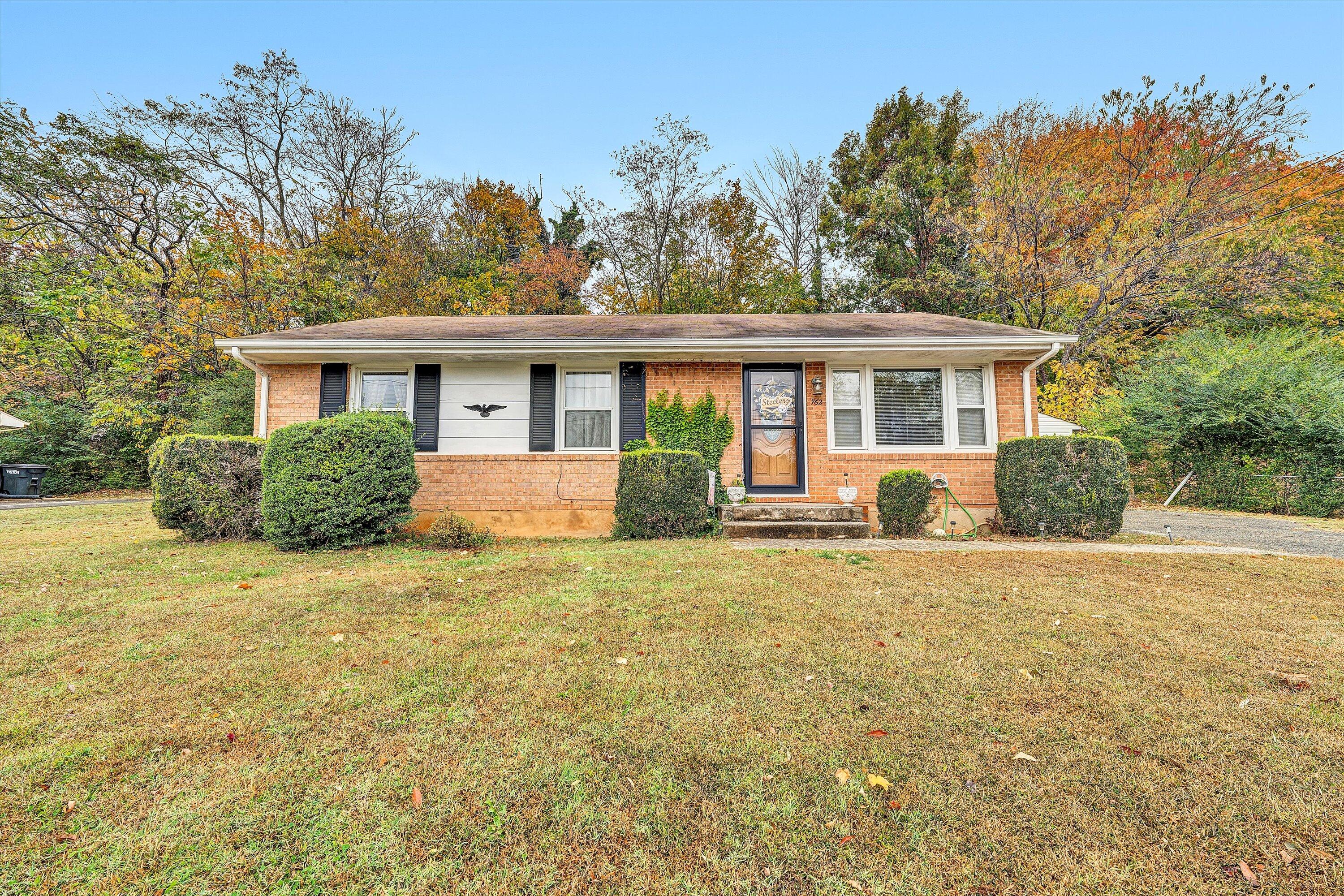 a front view of a house with a garden and trees