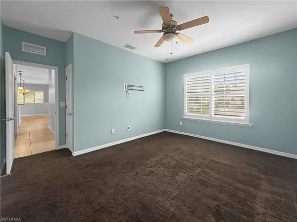 an empty room with a window and a fan