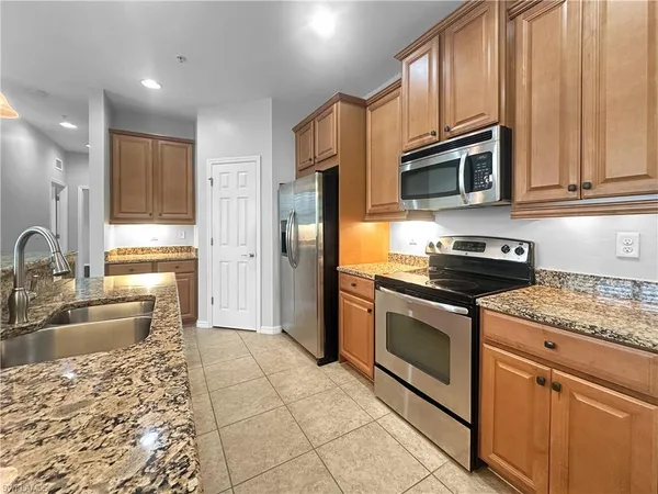 a large kitchen with kitchen island stainless steel appliances granite countertop a stove a sink a counter top space and cabinets