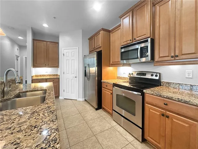 a large kitchen with kitchen island stainless steel appliances granite countertop a stove a sink a counter top space and cabinets