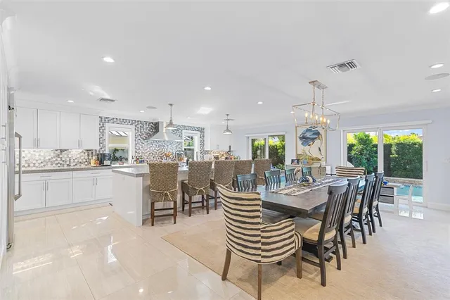 a dining room with furniture a chandelier and kitchen view