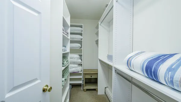 a close view of walk in closet with clothes and shoes