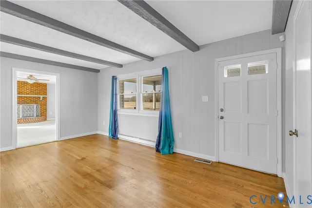 a view of an empty room with window and wooden floor