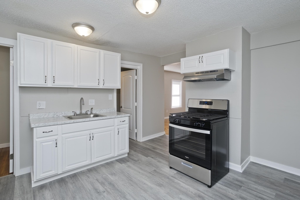 293 Eastern Avenue Springfield, MA 01109 - Photo 4 of 31 a kitchen with stainless steel appliances white cabinets and a sink