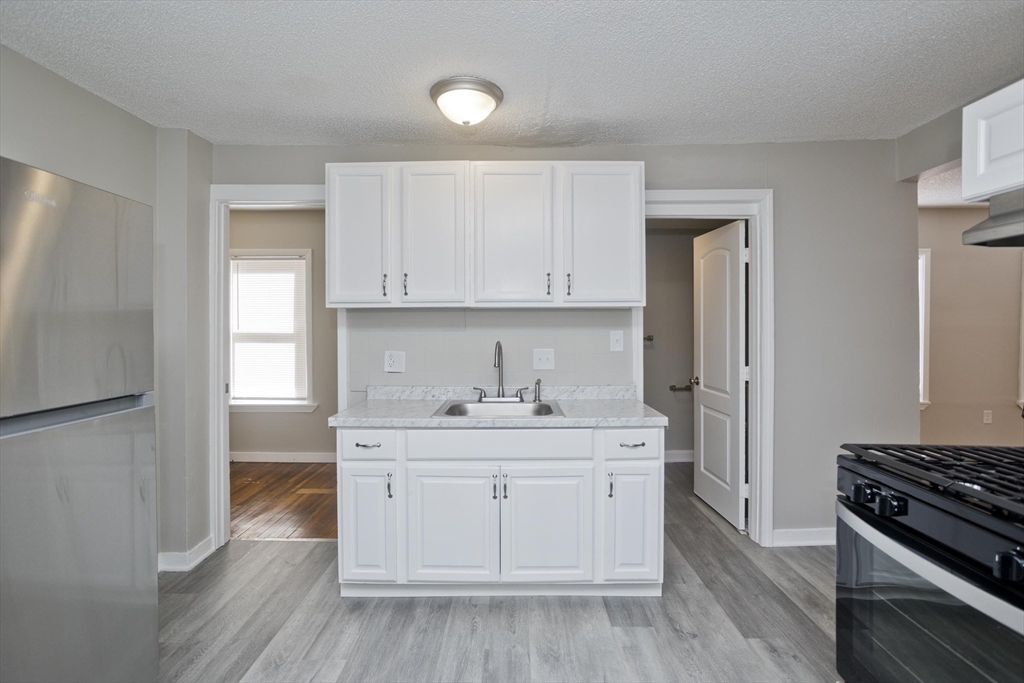 293 Eastern Avenue Springfield, MA 01109 - Photo 5 of 31 a kitchen with a sink stove and cabinets
