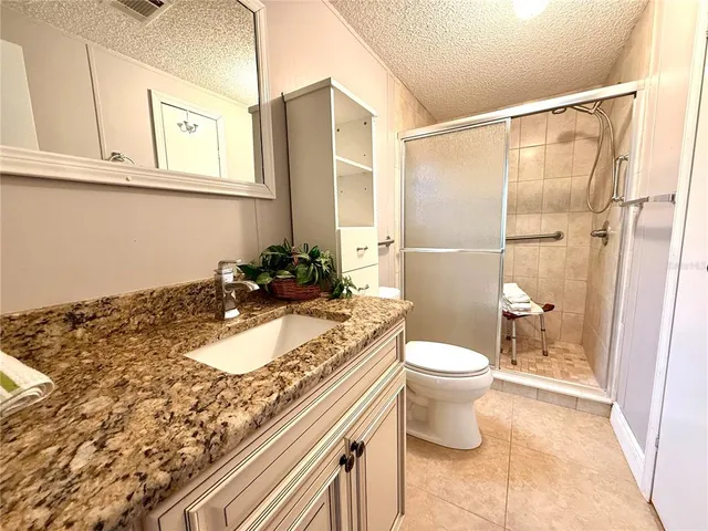 a bathroom with a granite countertop sink a toilet and a shower