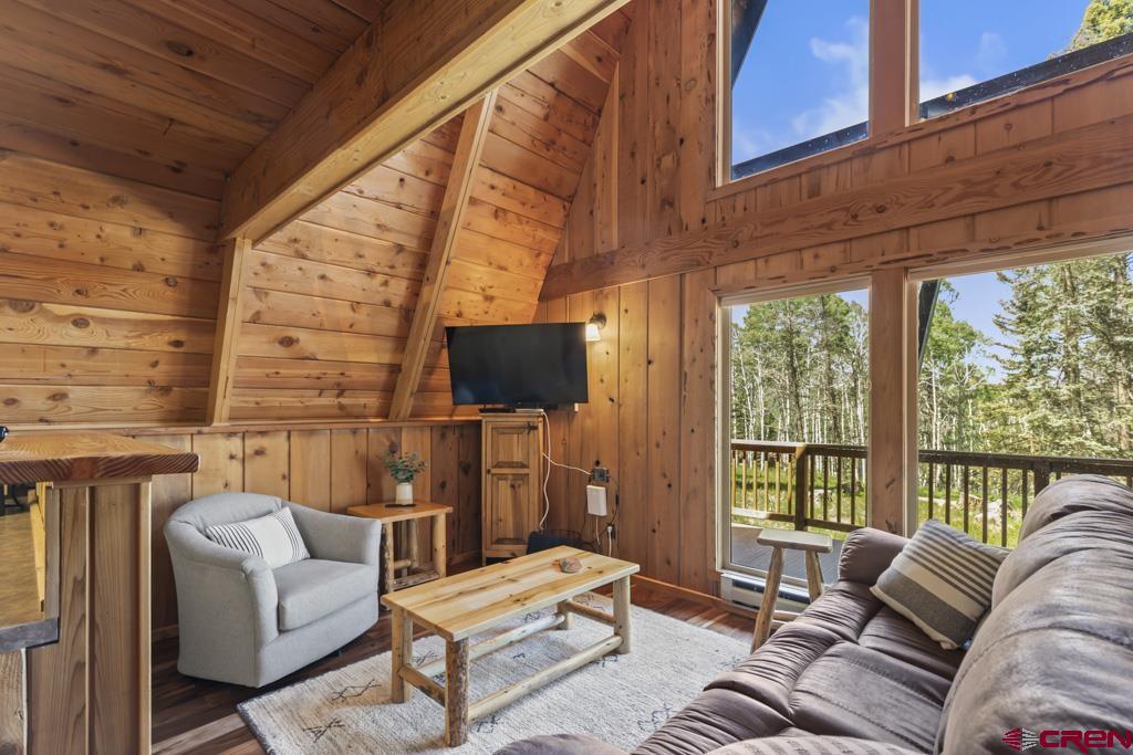 1201 Spruce Road Cimarron, CO 81220 - Photo 12 of 35 a living room with furniture a flat screen tv and a floor to ceiling window