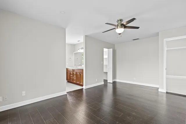 a view of an empty room with wooden floor and a ceiling fan