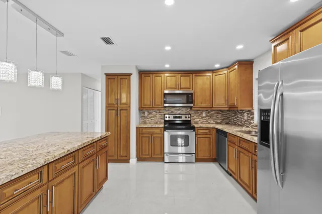 a kitchen with stainless steel appliances granite countertop a refrigerator a stove and a sink