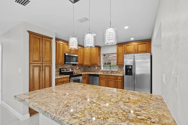 a kitchen with stainless steel appliances granite countertop a sink refrigerator and cabinets