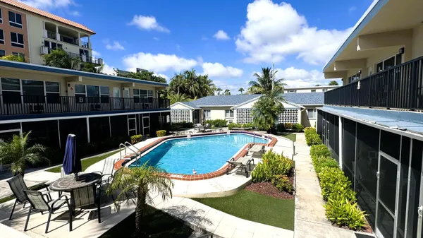 a view of a swimming pool with potted plants and wooden fence