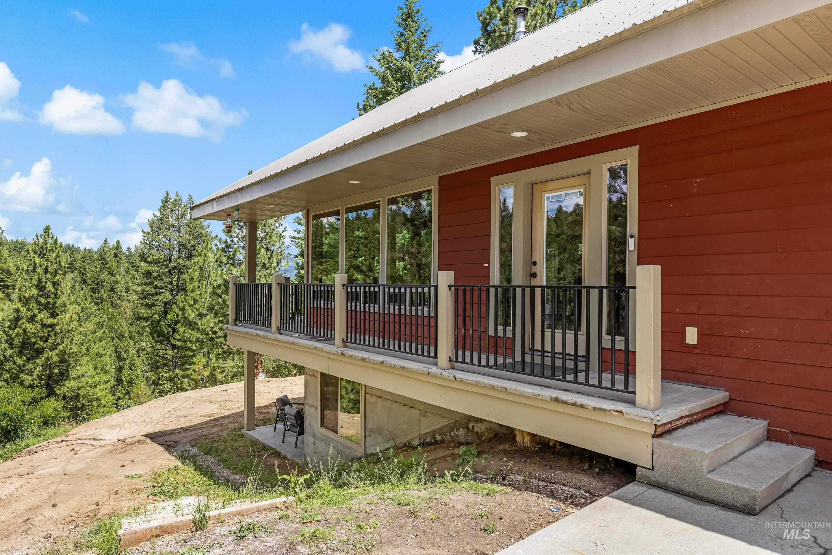 92 Cruickshank Road Horseshoe Bend, ID 83629 - Photo 2 of 50 Red-sided exterior with a covered deck, featuring a metal roof and concrete steps