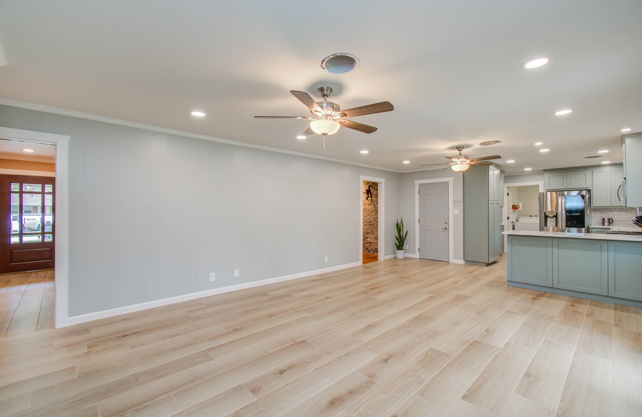 9002 Railton Street Houston, TX 77080 - Photo 6 of 32 a view of an empty room with a kitchen and a ceiling fan