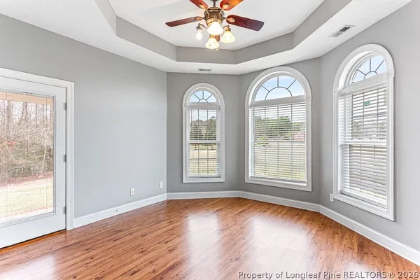 a view of empty room with wooden floor and fan