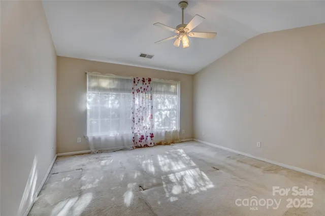 an empty room with windows and ceiling fan