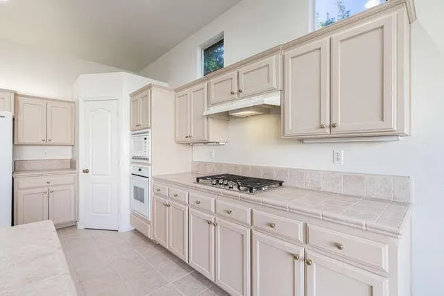 a kitchen with white cabinets and appliances