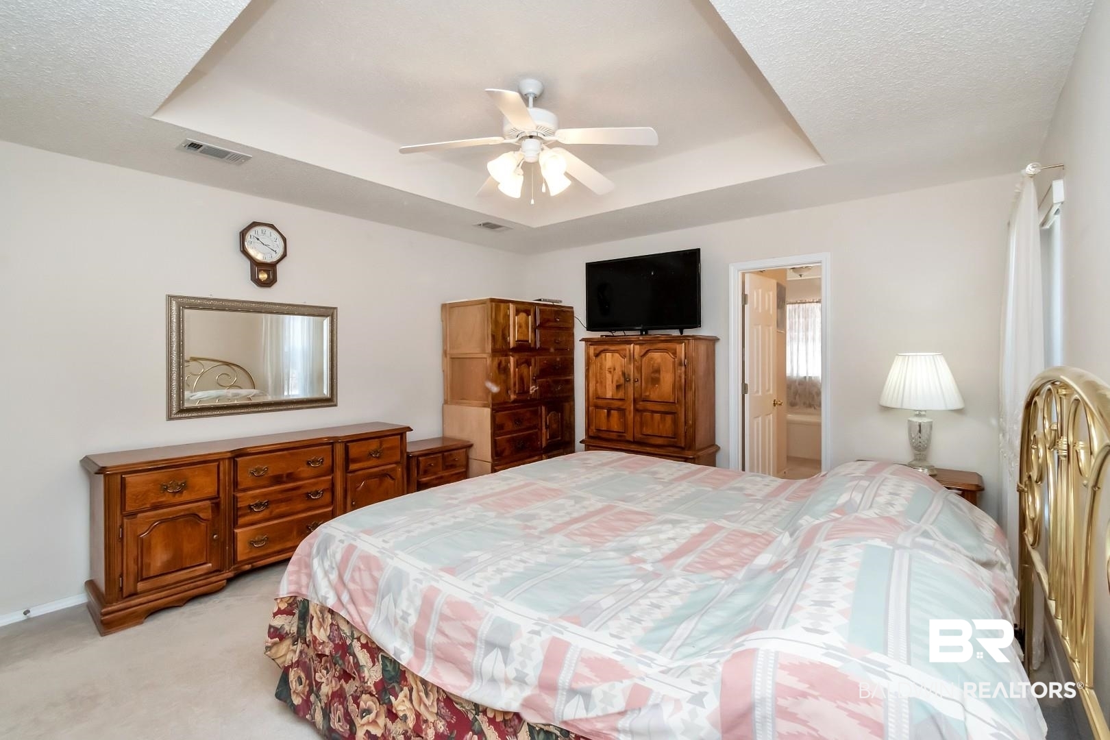 8221 Woodbend Drive Semmes, AL 36575 - Photo 19 of 35 Bedroom featuring ceiling fan, ensuite bathroom, light colored carpet, and a raised ceiling