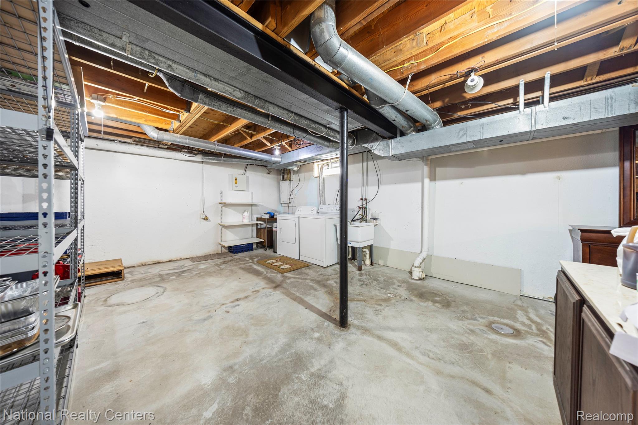 5274 East 14 Mile Road Warren, MI 48092 - Photo 25 of 31 Concrete flooring, exposed ceiling beams, built-in shelving, utility sink, and laundry appliance hookups