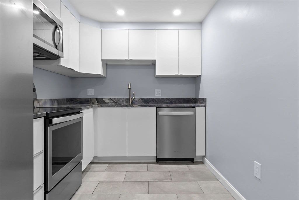 133 Franklin Street, Unit 503 Stoneham, MA 02180 - Photo 2 of 23 a kitchen with granite countertop white cabinets and stainless steel appliances