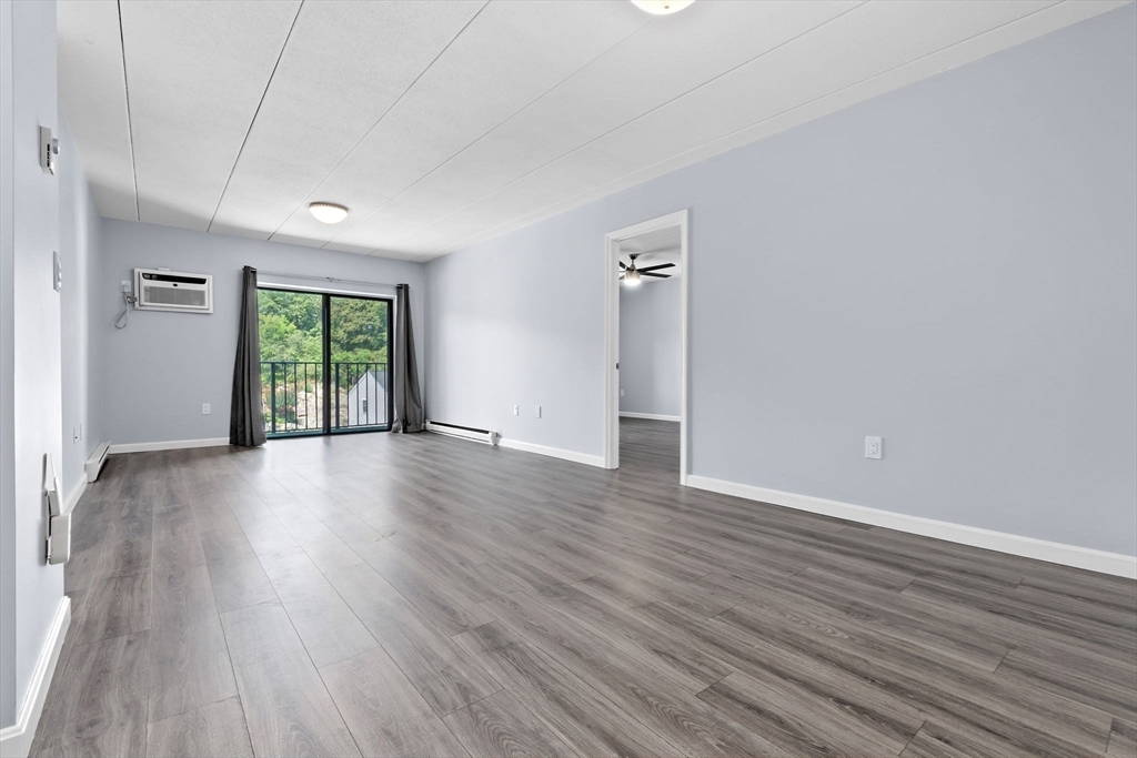 133 Franklin Street, Unit 503 Stoneham, MA 02180 - Photo 5 of 23 an empty room with wooden floor and windows