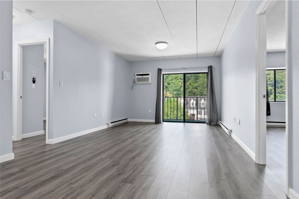 133 Franklin Street, Unit 503 Stoneham, MA 02180 - Photo 8 of 23 a view of an empty room with wooden floor and a window