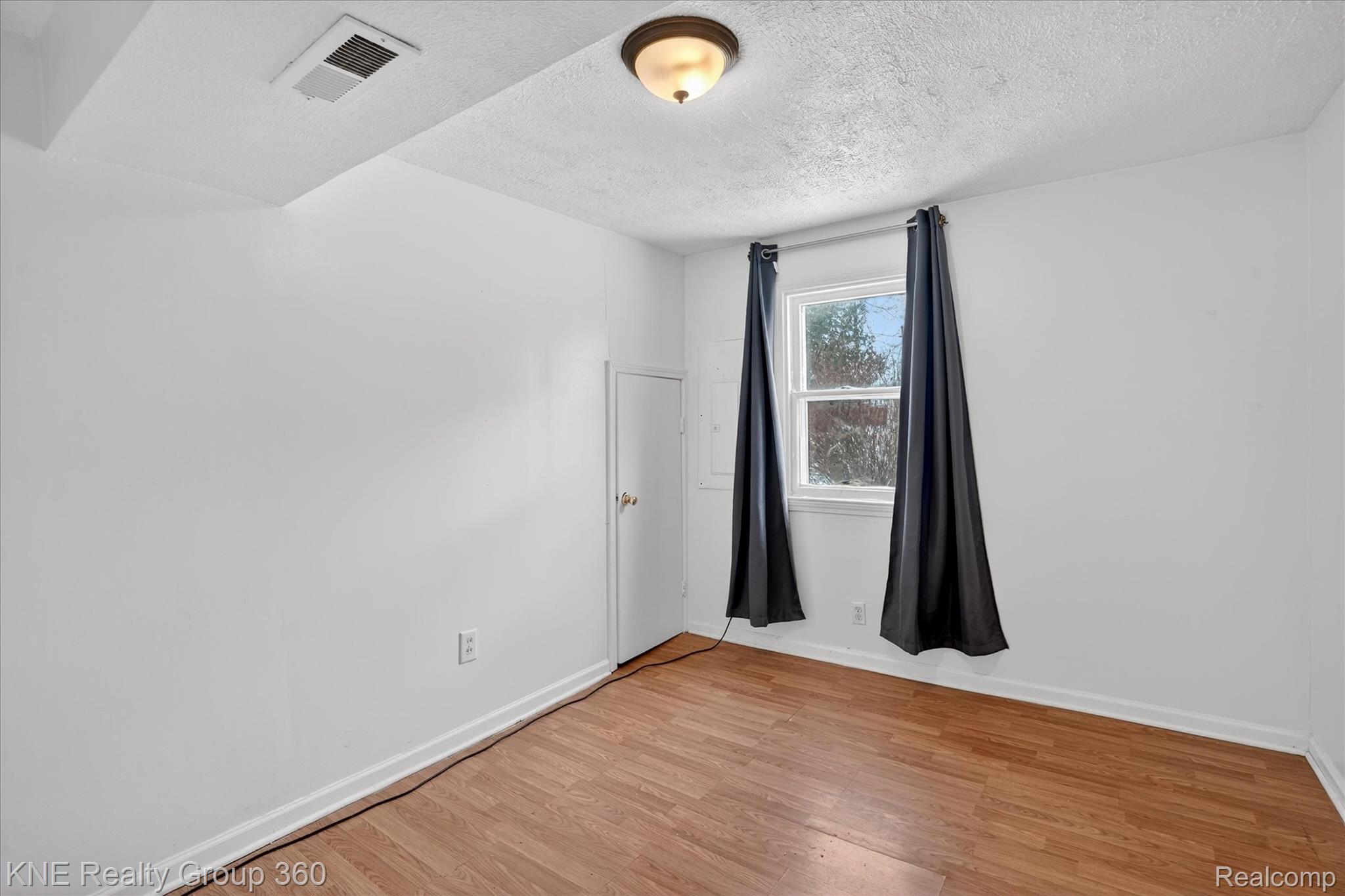 4928 Hughes Road Lansing, MI 48910 - Photo 22 of 35 Spare room with light wood-style flooring and a textured ceiling