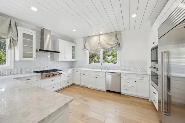 a large kitchen with stainless steel appliances granite countertop a stove a sink dishwasher and a refrigerator