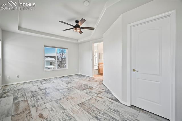 10165 Angeles Road Peyton, CO 80831 - Photo 23 of 38 Tiled empty room with a tray ceiling and ceiling fan