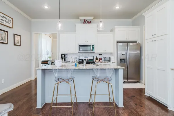 a kitchen with stainless steel appliances a refrigerator a stove a sink cabinets and wooden floor