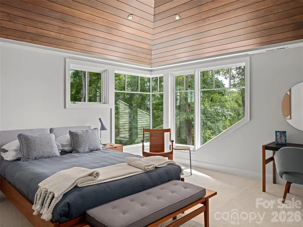 a bedroom with a bed a large window with table and chairs