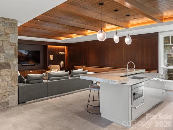 a living room with stainless steel appliances kitchen island granite countertop a sink and a large window