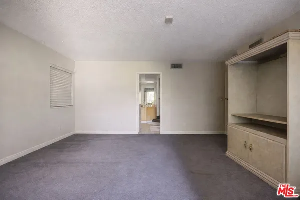 a view of an empty room with window and closet area