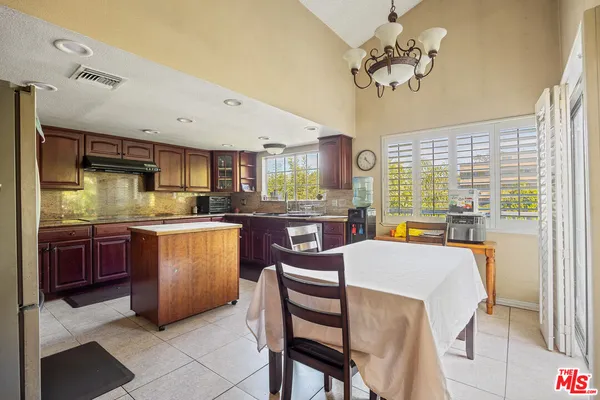 a kitchen with stainless steel appliances granite countertop a stove top oven a sink dishwasher a dining table and chairs with wooden floor