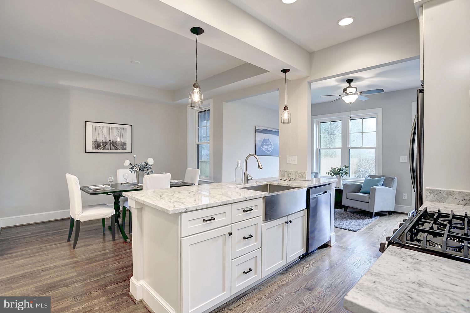 17 16th Street Southeast Washington, DC 20003 - Photo 9 of 29 a large white kitchen with a stove a sink a dining table and chairs with wooden floor