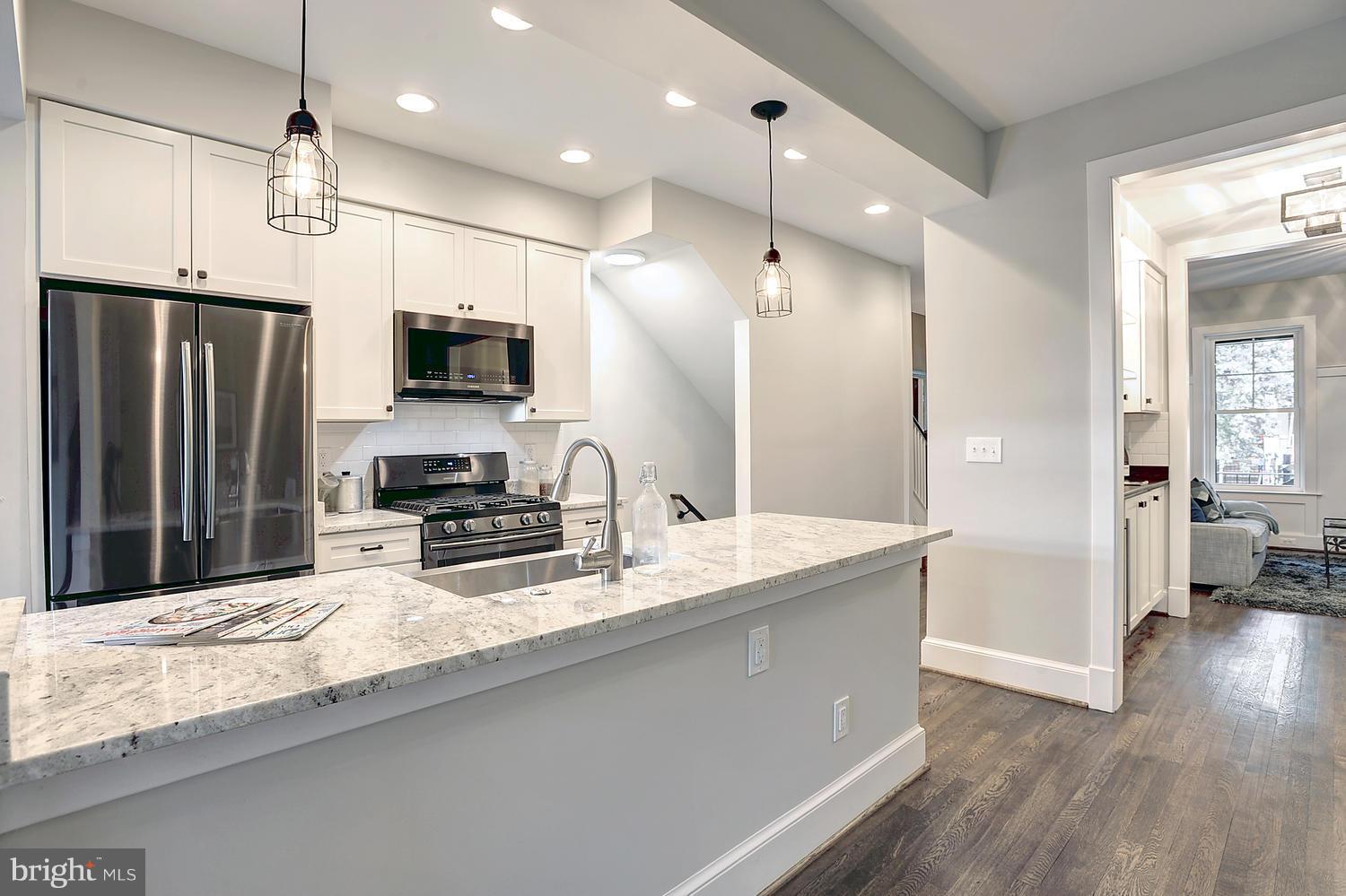 17 16th Street Southeast Washington, DC 20003 - Photo 10 of 29 a large kitchen with granite countertop a large counter top stainless steel appliances and wooden floor