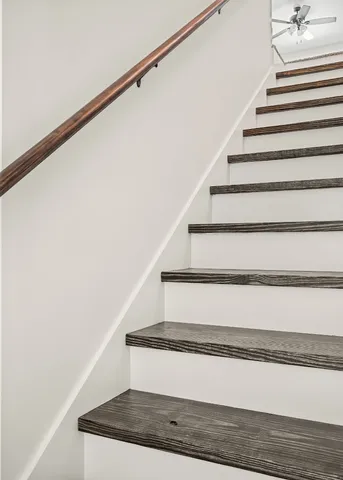 an empty room with chandelier fan and windows
