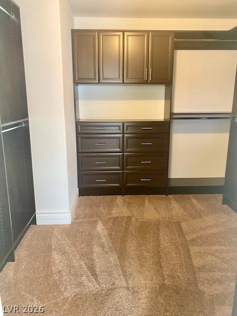 159 Tall Ruff Drive Las Vegas, NV 89148 - Photo 19 of 31 Custom built-in cabinetry provides abundant storage solutions alongside plush carpeting in this walk-in closet.