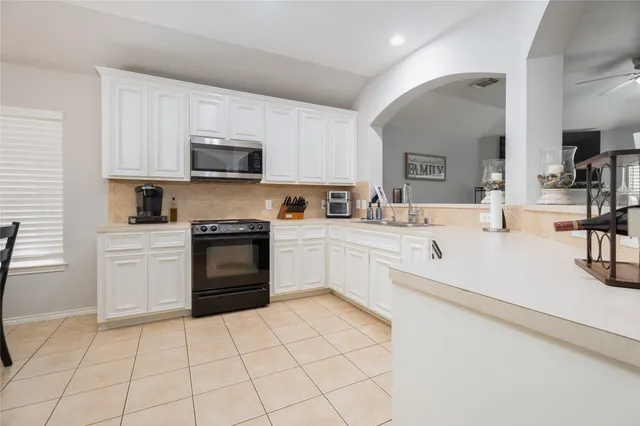 a kitchen with a sink a stove top oven and white cabinets