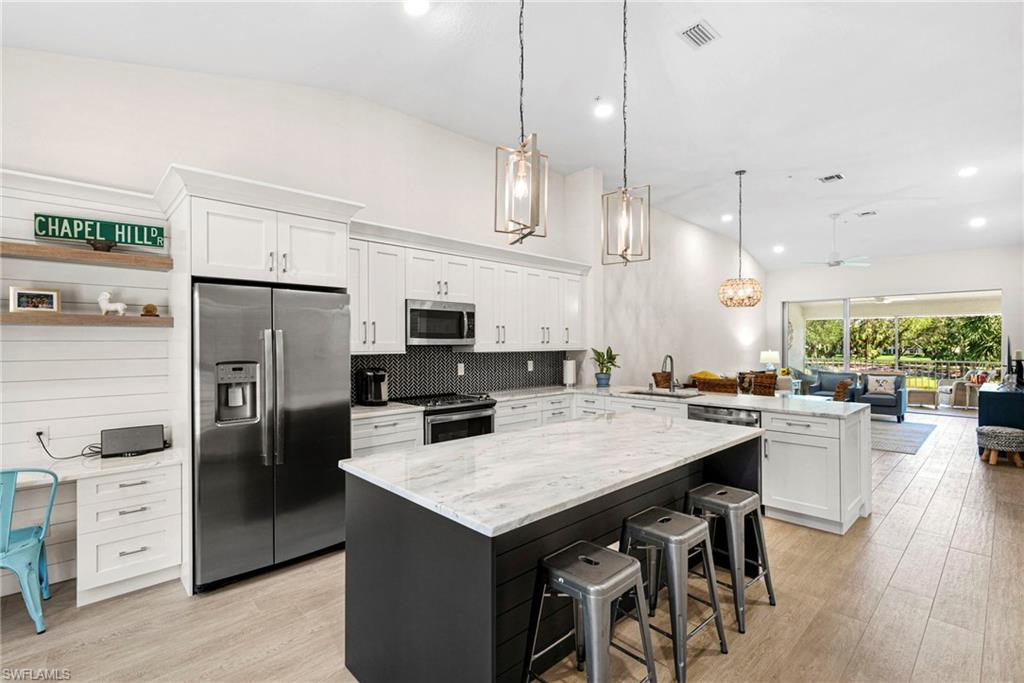 a kitchen with stainless steel appliances a stove a refrigerator a sink a stove a dining table and chairs