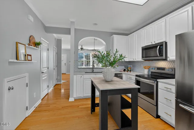 a kitchen with stainless steel appliances granite countertop a stove a sink a microwave refrigerator and a dining table with wooden floor