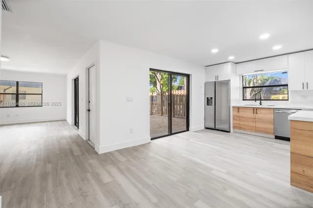 a view of a big room with wooden floor and windows